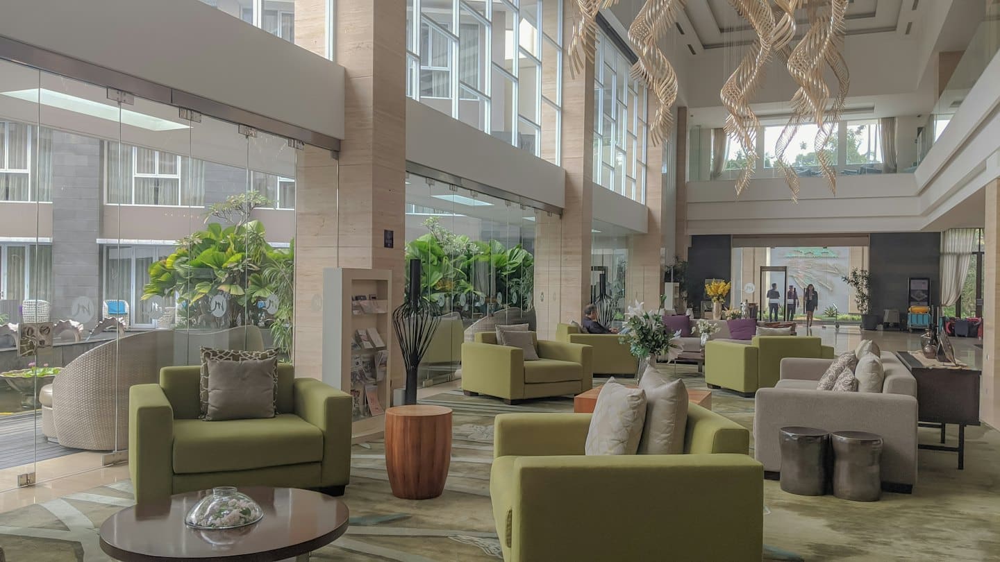 Modern hotel lobby with green chairs and sofas.